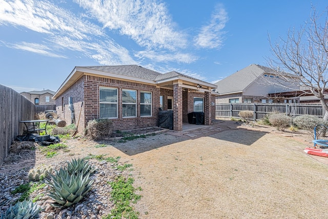 view of front of property with a fenced backyard, a patio, and brick siding