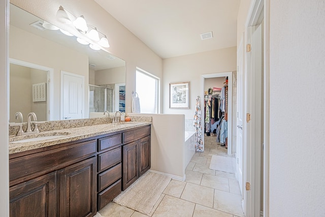 full bathroom with a spacious closet, a stall shower, a sink, and visible vents