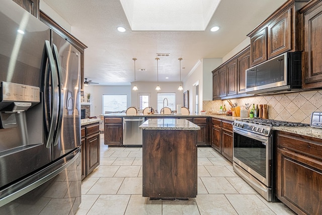 kitchen with stainless steel appliances, visible vents, a peninsula, and decorative backsplash