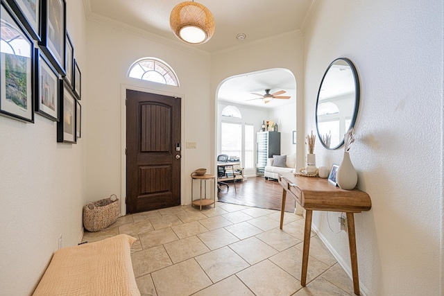 entrance foyer featuring arched walkways, ornamental molding, and a ceiling fan