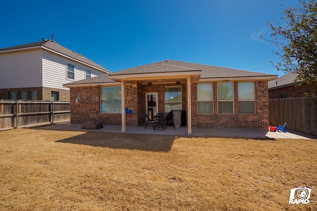 rear view of house featuring a patio, brick siding, and a fenced backyard