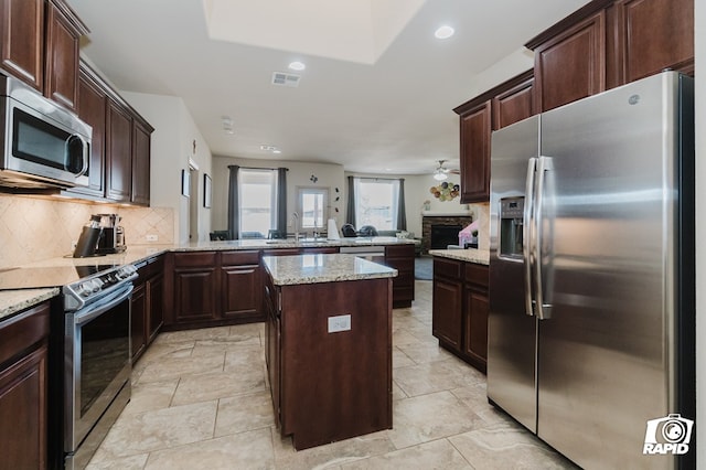 kitchen with stainless steel appliances, visible vents, backsplash, a kitchen island, and a peninsula