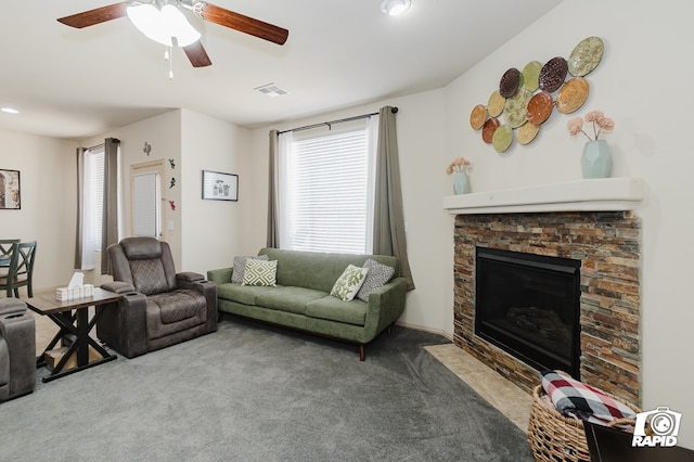 living area with a ceiling fan, a stone fireplace, carpet flooring, and visible vents