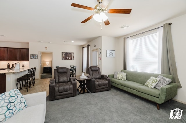 living area with a ceiling fan, light colored carpet, visible vents, and light tile patterned flooring