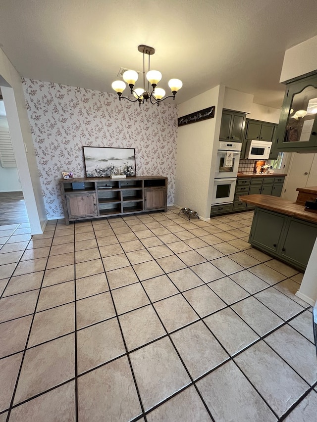 kitchen with butcher block counters, light tile patterned floors, white appliances, green cabinetry, and an inviting chandelier