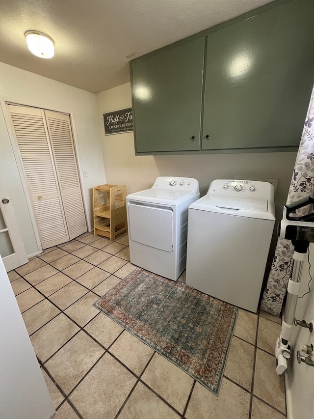 laundry area featuring cabinets, washer and clothes dryer, a textured ceiling, and light tile patterned floors