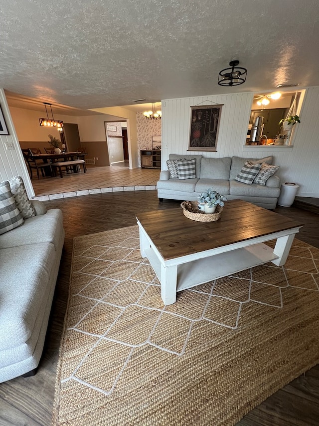 living room featuring hardwood / wood-style flooring, a textured ceiling, and an inviting chandelier