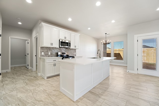 kitchen with appliances with stainless steel finishes, a center island with sink, white cabinetry, and sink