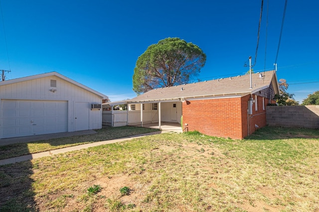 back of house featuring a garage, a yard, and an outbuilding