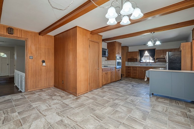 kitchen with sink, an inviting chandelier, beamed ceiling, pendant lighting, and appliances with stainless steel finishes