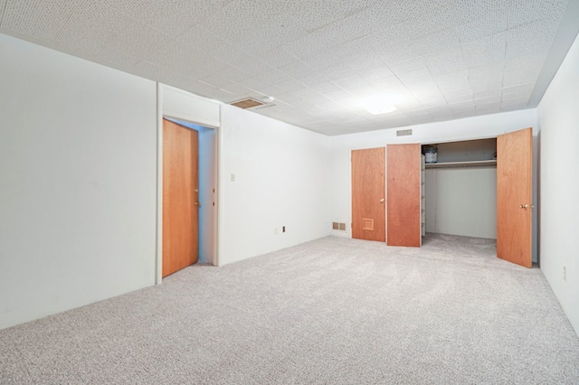 unfurnished bedroom featuring light carpet and a closet