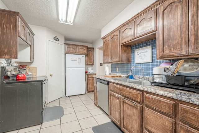 kitchen featuring appliances with stainless steel finishes, sink, decorative backsplash, light tile patterned floors, and a textured ceiling