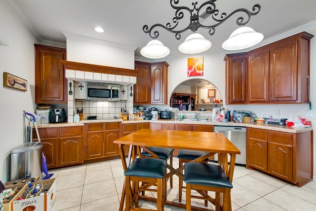 kitchen with pendant lighting, appliances with stainless steel finishes, ornamental molding, light tile patterned flooring, and decorative backsplash