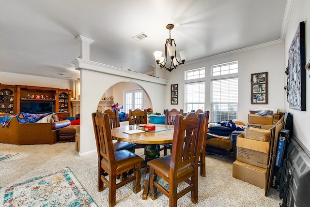 carpeted dining area with an inviting chandelier and ornamental molding