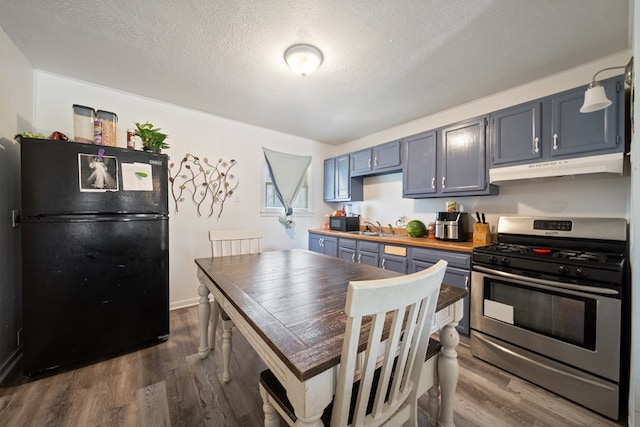 1213 Ridgeroad Dr, Big Spring, TX 79720 - kitchen featuring black appliances, under cabinet range hood, dark wood-type flooring, a textured ceiling, and blue cabinets