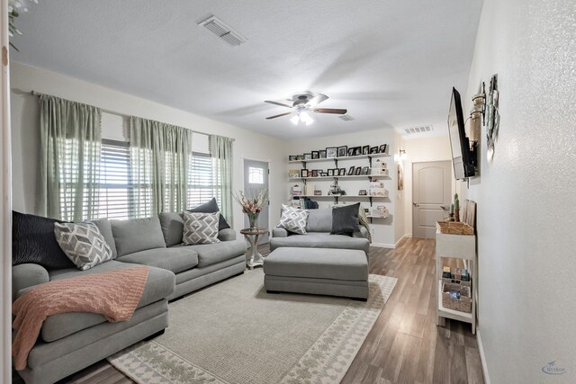living room with hardwood / wood-style floors, ceiling fan, and a textured ceiling