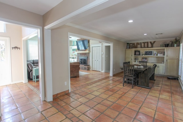 unfurnished dining area featuring tile patterned flooring, ornamental molding, and a fireplace