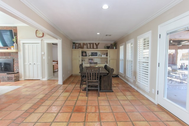 tiled dining room featuring crown molding and a brick fireplace