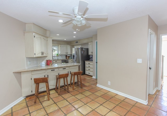 kitchen featuring a breakfast bar, stainless steel refrigerator with ice dispenser, light stone counters, white cabinets, and kitchen peninsula