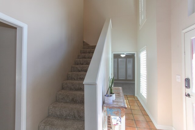 stairs featuring a towering ceiling and tile patterned flooring