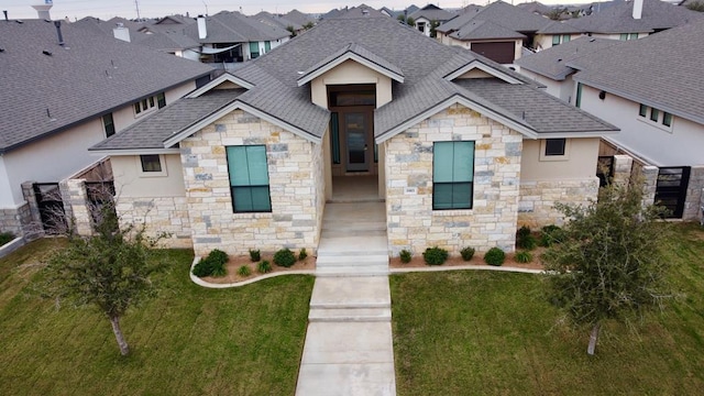 view of front of property with a shingled roof, a front yard, and a residential view