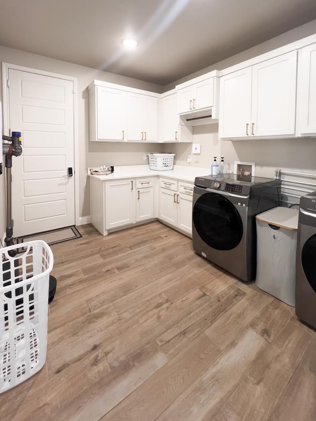 laundry area featuring washer / dryer, cabinet space, and light wood-style floors