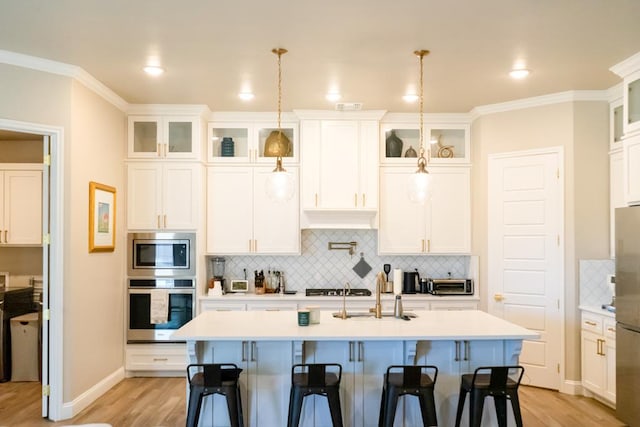 kitchen featuring stainless steel appliances, white cabinetry, light wood finished floors, and a kitchen breakfast bar