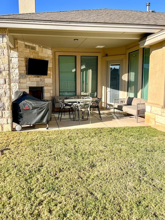 rear view of property with stone siding, a yard, a patio, and roof with shingles