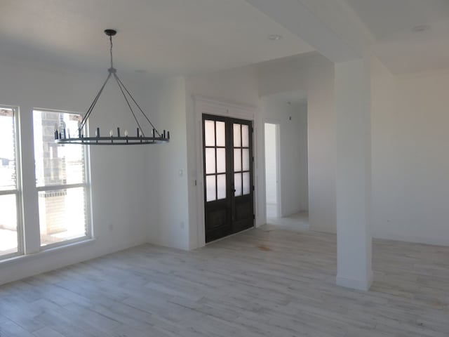 unfurnished dining area with light wood-type flooring, a wealth of natural light, and french doors