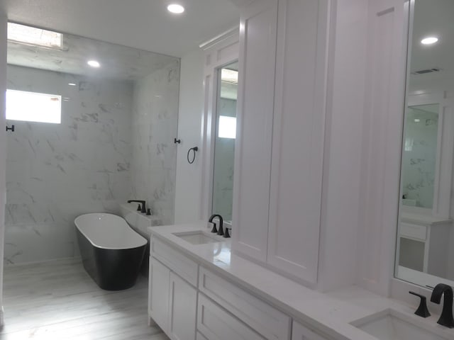 bathroom with a bathing tub, vanity, and hardwood / wood-style flooring