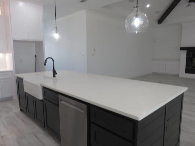 kitchen with white cabinets, decorative light fixtures, light hardwood / wood-style floors, and an island with sink