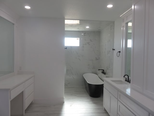 bathroom with a bathtub, wood-type flooring, tile walls, and vanity