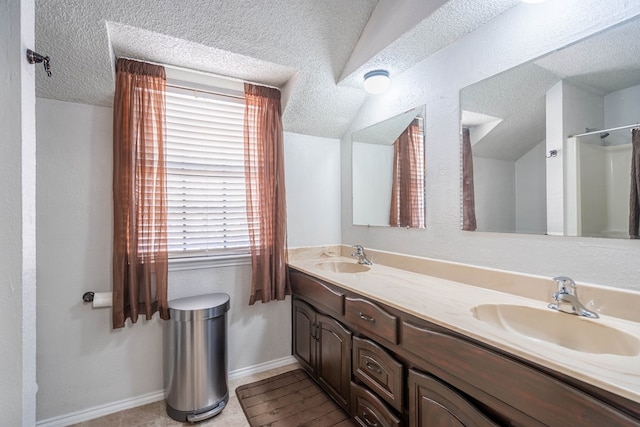 bathroom featuring a sink, lofted ceiling, a textured ceiling, and double vanity