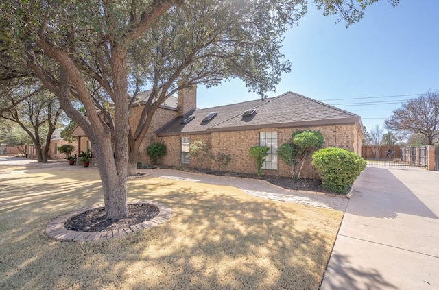 view of front of home featuring brick siding, a shingled roof, fence, a chimney, and a gate