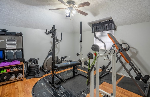 exercise room with ceiling fan, a textured ceiling, wood finished floors, and vaulted ceiling