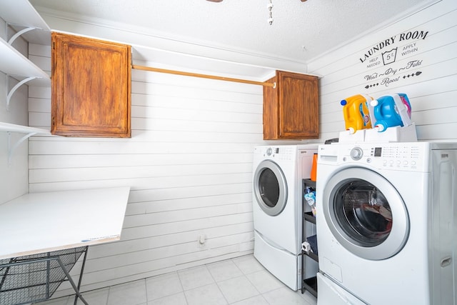 laundry room with crown molding, washer and clothes dryer, light tile patterned floors, cabinet space, and a textured ceiling