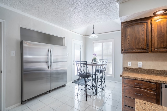 kitchen featuring dark brown cabinets, backsplash, light tile patterned floors, freestanding refrigerator, and a textured ceiling