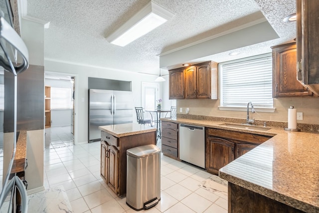 kitchen featuring a sink, stainless steel appliances, a healthy amount of sunlight, and a center island