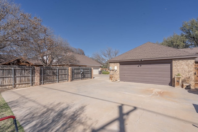 view of property exterior with a garage, brick siding, roof with shingles, and fence