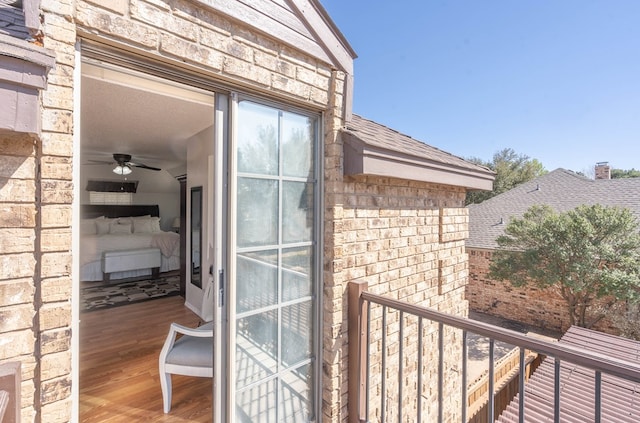 property entrance with a balcony, brick siding, and roof with shingles