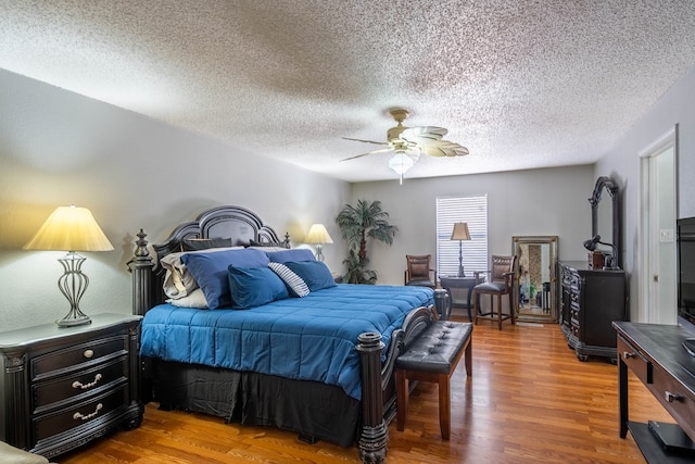 bedroom with a textured ceiling, wood finished floors, and ceiling fan