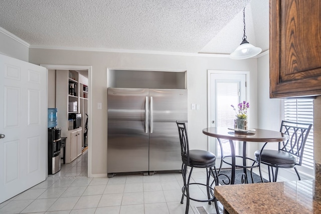 kitchen featuring light tile patterned floors, freestanding refrigerator, ornamental molding, hanging light fixtures, and a textured ceiling