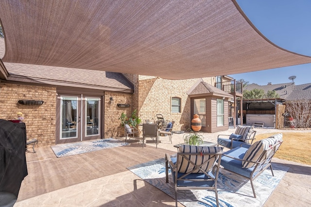 view of patio featuring french doors, a balcony, and a hot tub