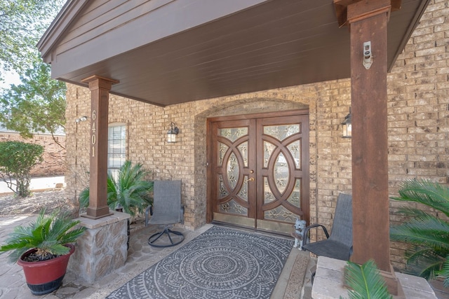 doorway to property with brick siding and covered porch