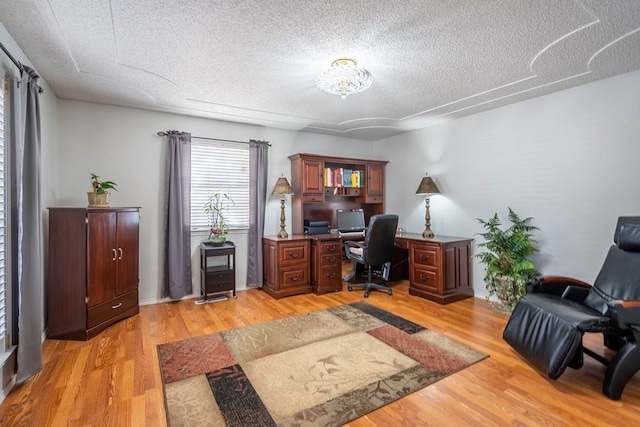 office with light wood-style flooring and a textured ceiling