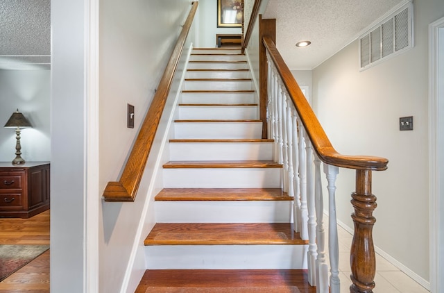 stairway featuring visible vents, a textured ceiling, wood finished floors, recessed lighting, and baseboards