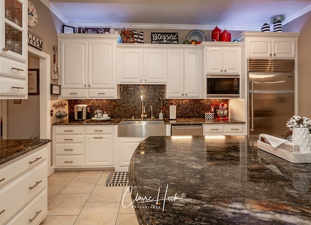 kitchen with sink, white cabinetry, built in appliances, ornamental molding, and decorative backsplash