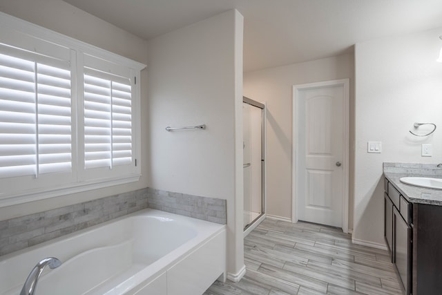 807 Bronco Ct, Midland, TX 79705 - bathroom featuring a garden tub, a stall shower, vanity, and wood finished floors