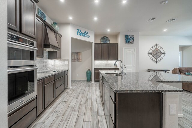 807 Bronco Ct, Midland, TX 79705 - kitchen with stainless steel double oven, tasteful backsplash, dark stone counters, dark brown cabinets, and recessed lighting