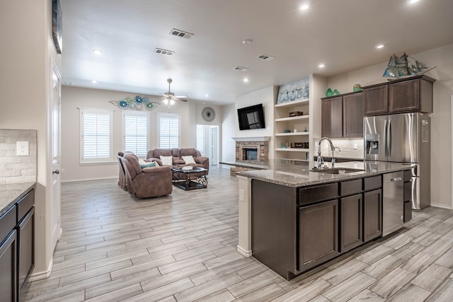 807 Bronco Ct, Midland, TX 79705 - kitchen featuring dark brown cabinetry, appliances with stainless steel finishes, light wood-style flooring, a brick fireplace, and recessed lighting